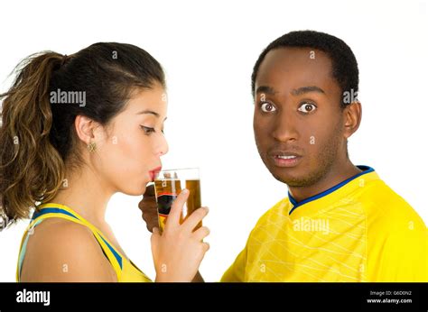 Charming Interracial Couple Wearing Yellow Football Shirts Posing For Camera While Woman Drinks