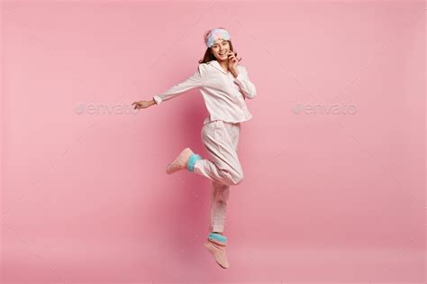 Indoor Shot Of Overjoyed European Woman Raises Leg Spreads Hand Wears