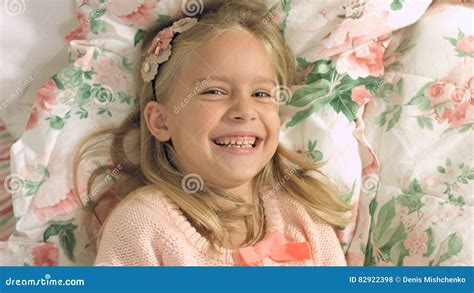 Adorable Little Girl Lying On The Bed And Laughing Gaily Stock Photo