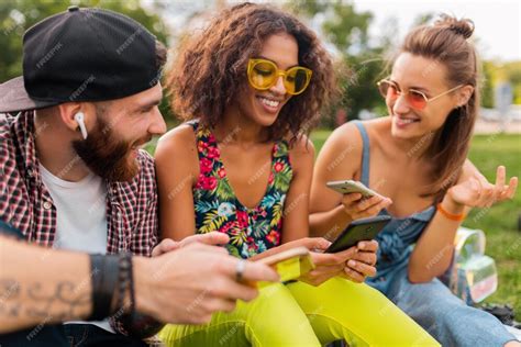 Feliz Joven Compañía De Amigos Sonrientes Sentados En El Parque Usando