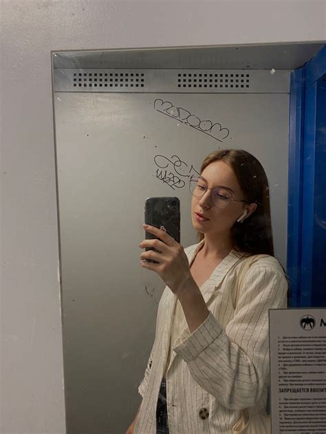A Woman Taking A Selfie In Front Of A Mirror With Writing On The Wall