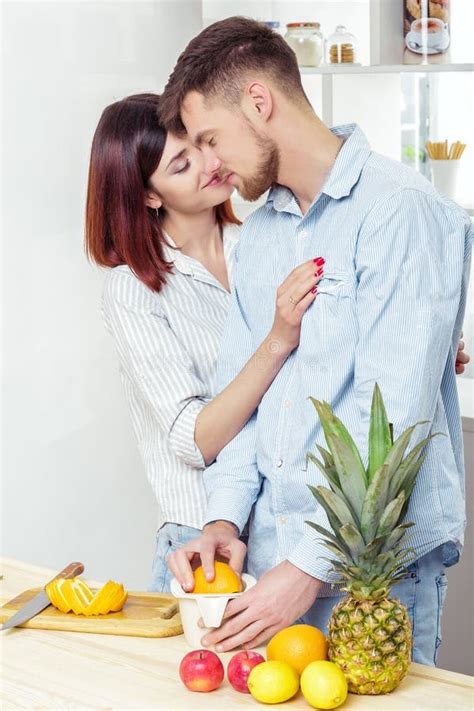 Happy Couple In Love In Kitchen Making Healthy Juice From Fresh Orange