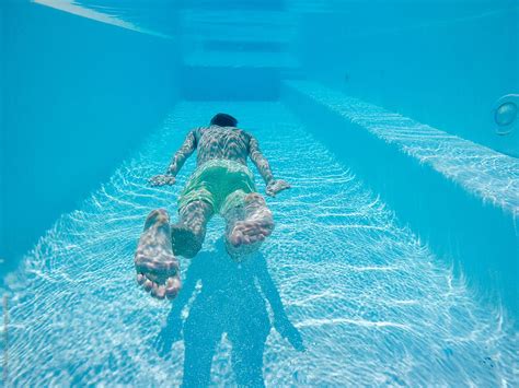 underwater shot of man floating in swimming pool by stocksy contributor urs siedentop and co