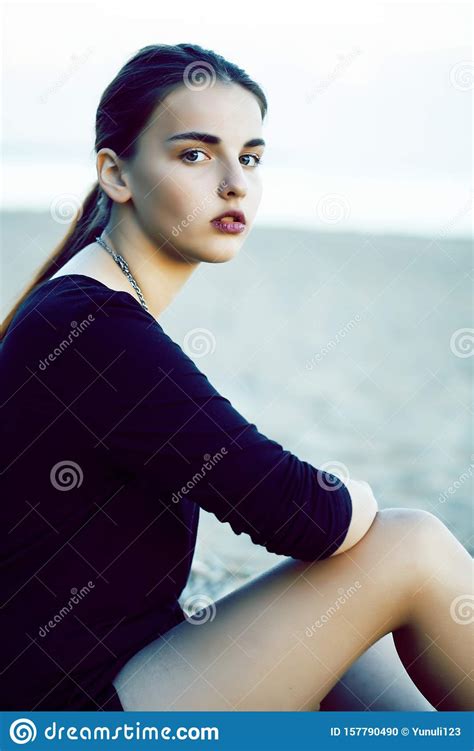 Young Pretty Brunette Girl With Long Hair Waiting Alone On Sand At Seacoast Lifestyle People