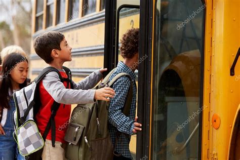 Niños De La Escuela Subiendo A Un Autobús Escolar Fotografía De Stock
