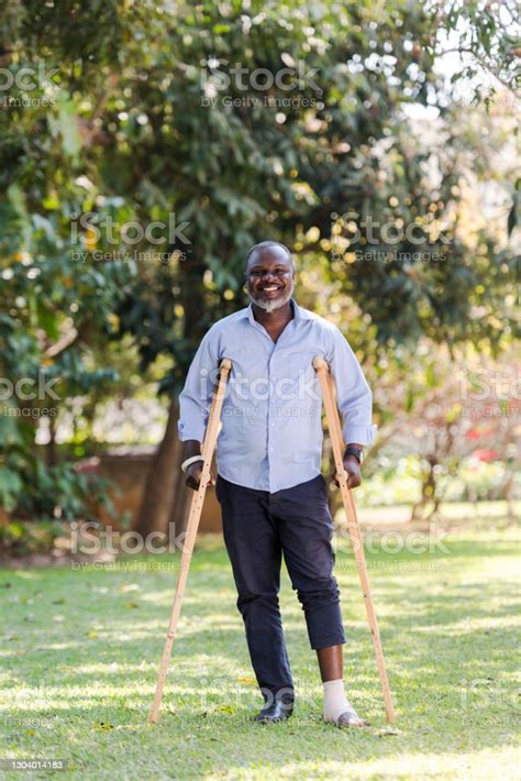 Full Length Portrait Injured African Man Standing With Crutches Stock