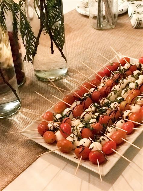 a platter filled with tomatoes and skewers on top of a wooden table
