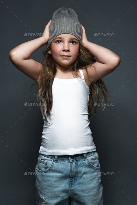 Little Girl Model Professionally Posing In The Studio In Jeans And A