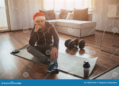 Young Ordinary Man Go In For Sport At Home Sad Upset And Bored Guy In Red Hat Sit On Mat After