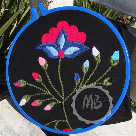 A Black And Blue Embroidered Bag With Flowers On The Front Is Sitting