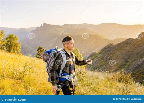 Hipster Young Man With Backpack Enjoying Sunset On Peak Mountain Stock