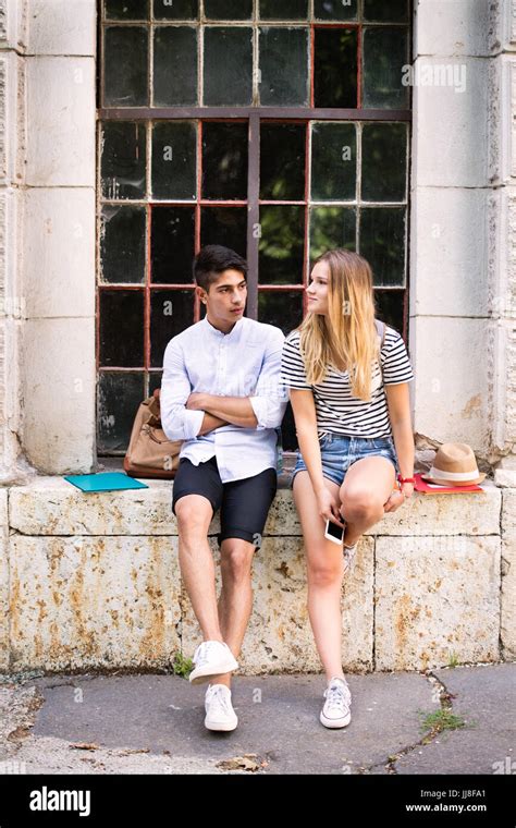 Attractive Teenage Student Couple Posing In Front Of University Stock