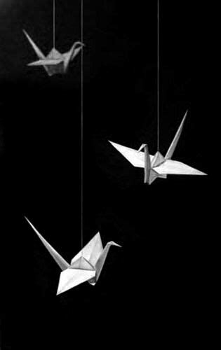 Three White Origami Birds Suspended From Strings In The Dark Sky With