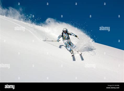 Skier On A Steep Mountain Slope In Turn Raises The Snow Dust Stock