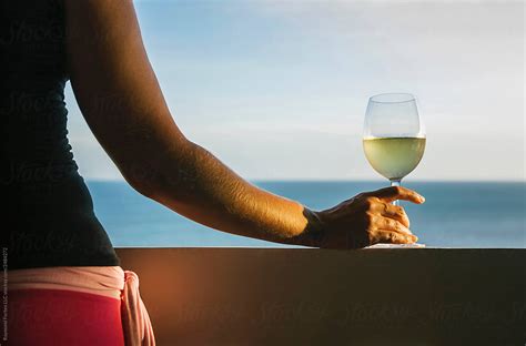 woman holding wine glass by the beach by raymond forbes llc luxury wine stocksy united