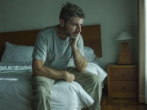 Dramatic Lifestyle Portrait Of 30s To 40s Handsome Man Sitting Sad On Bed Feeling Worried And