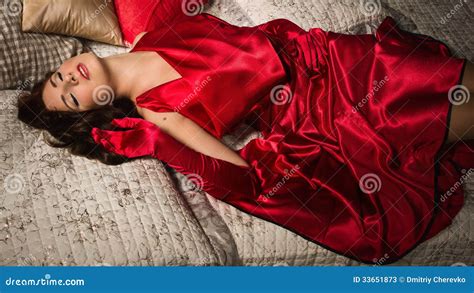 Sensual Brunette In A Red Dress Lying On The Bed Stock Photos Image