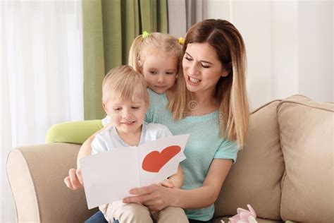 Mother Receiving Greeting Card From Her Cute Little Children At Home