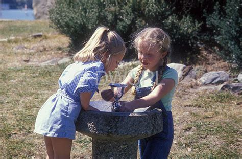 A Royalty Free Image Of Two Little Girls At Drinking Bubbler