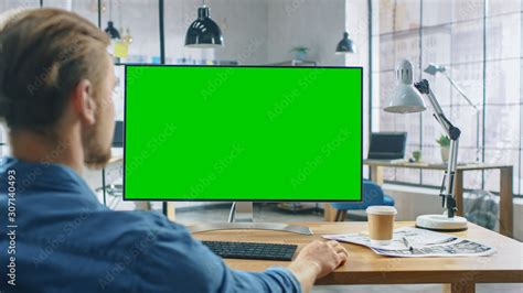 Over The Shoulder Shot Man Uses Desktop Computer With Green Mock Up