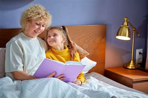 pleasant granny and daughter read a book before bed evening ritual before bedtime stock image