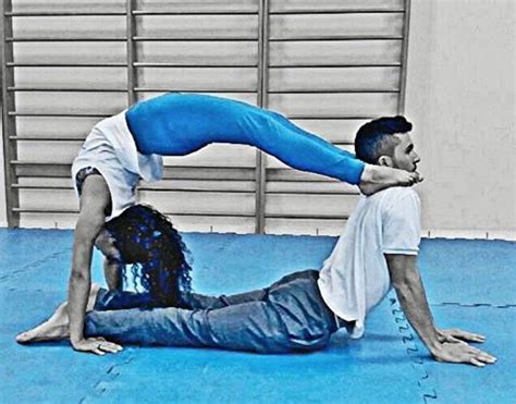 A Man And Woman Are Doing Acrobatic Exercises On The Blue Mat In An