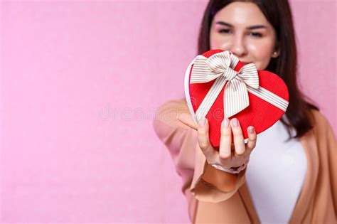 T Box In The Shape Of A Heart In The Hands Of A Young Asian Girl On A Pink Isolated