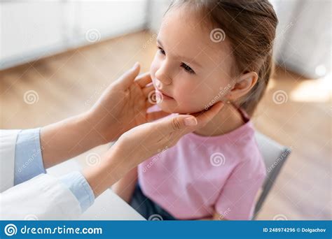 Doctor Checking Girl Patientand X27s Tonsils At Clinic Stock Photo