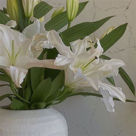 Some White Flowers Are In A Vase On A Counter Top With Marble Walls