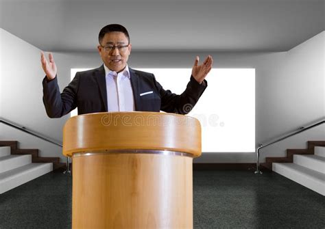Businessman On Podium Speaking At Conference With Screen Stock Photo