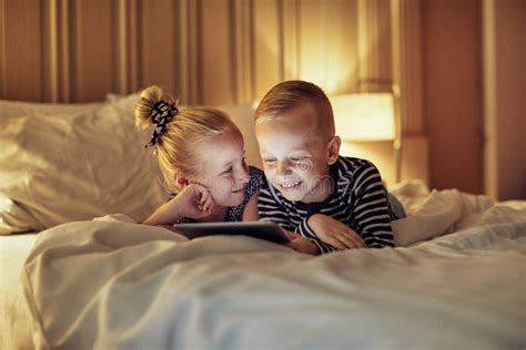 lach op broertje en zusje die video s bekijken voor het slapen gaan stock afbeelding image of