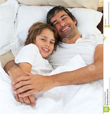 Loving Father Hugging His Son Lying On The Bed Stock