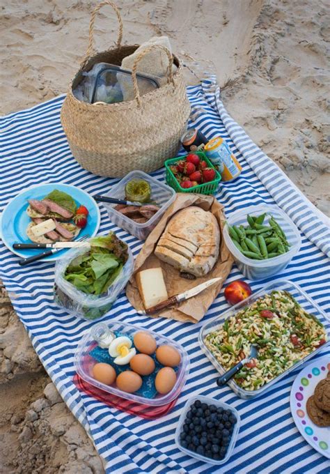 a blue and white striped towel with food on it including bread salads eggs fruit and vegetables