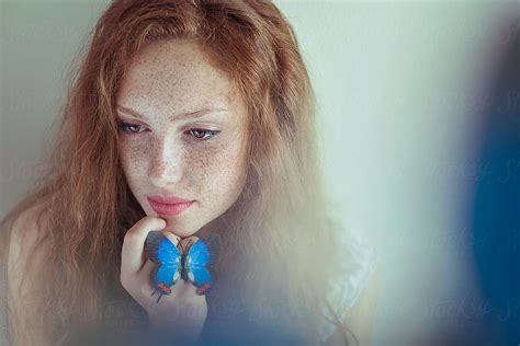 Beautiful Young Redhead Woman With Freckles Holding A Blue Butterfly