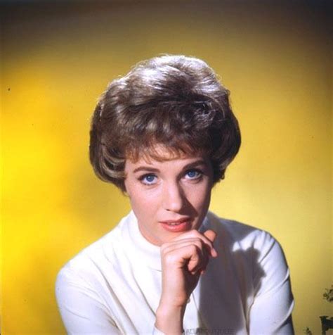 A Woman With Short Hair And Blue Eyes Posing For A Photo In Front Of A Yellow Background