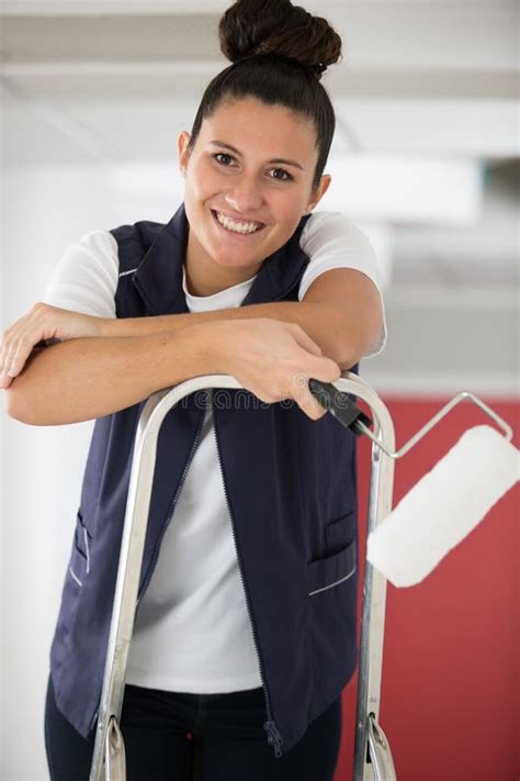 Happy Smiling Woman Standing On Ladder Painting Walls Stock Photo