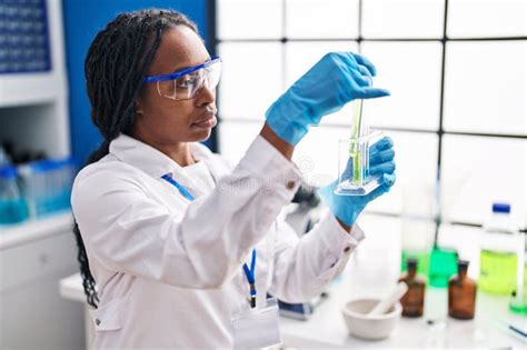 African American Woman Wearing Scientist Uniform Measuring Liquid