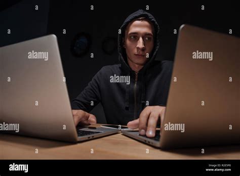 Portrait Of Hacker In Black Hoodie Using Laptops In Dark Room Cyber