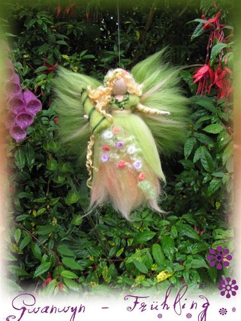 A Green Fairy Doll Sitting In The Middle Of Some Bushes And Flowers