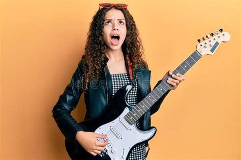 Teenager Hispanic Girl Playing Electric Guitar Angry And Mad Screaming