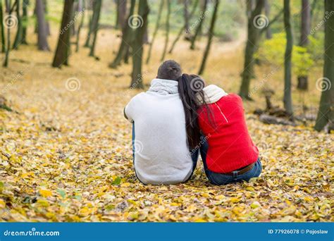 Beautiful Couple In Autumn Park Sitting On The Ground Stock Photo