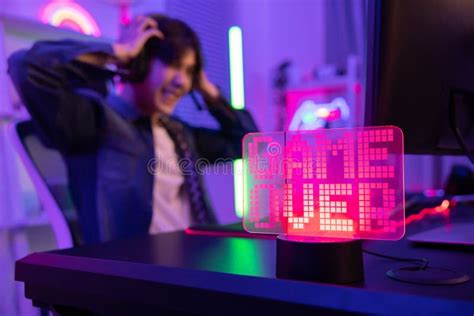 Game Over Neon Sign With Blurred Upset Gamer Losing The Game Stock