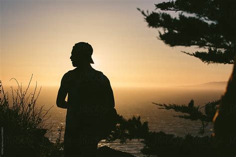 A Young Man Watches The Sunset Over The Pacific Ocean By Stocksy