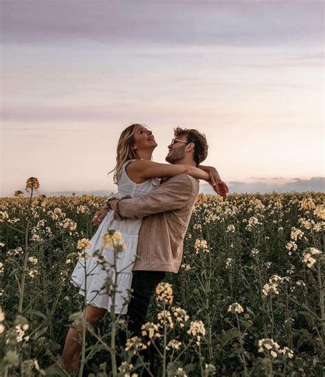 A Man And Woman Embracing In A Field Of Flowers