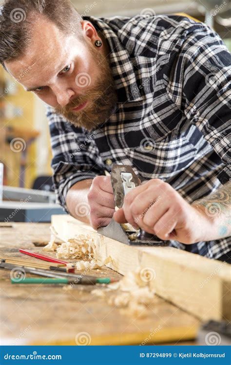 Focused Carpenter Work With Plane On Wood Plank In Workshop Stock Image