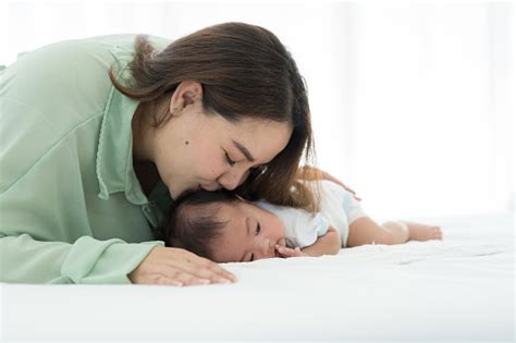 Ibu Muda Asia Yang Bahagia Merawat Dan Mencium Bayinya Yang Baru Lahir