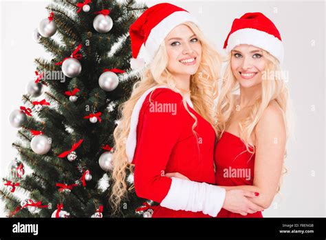 Cheerful Blonde Sisters Twins In Red Santa Claus Clothes And Hats