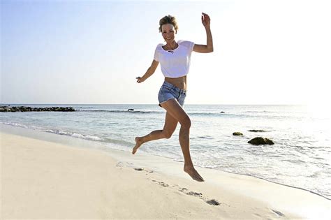Beautiful Woman Running And Jumping For Joy On The Beach Stock Photo