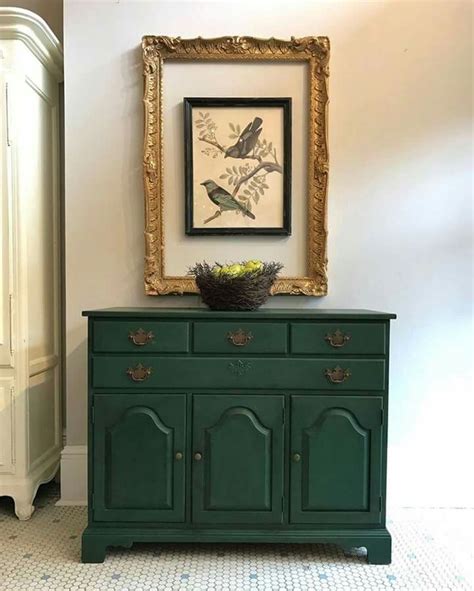 A Green Dresser With A Painting On The Wall Above It