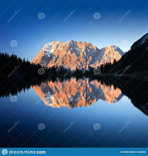 Mount Zugspitze With Alpenglow Reflecting In Mountain Lake Stock Photo